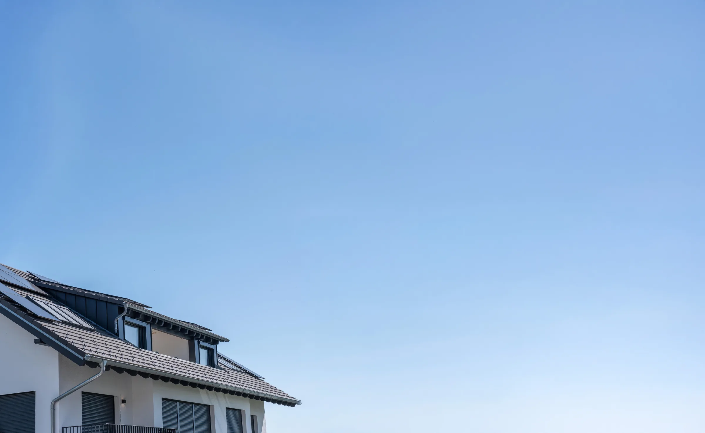 Ziegeldach eines Wohnhauses vor blauem Himmel