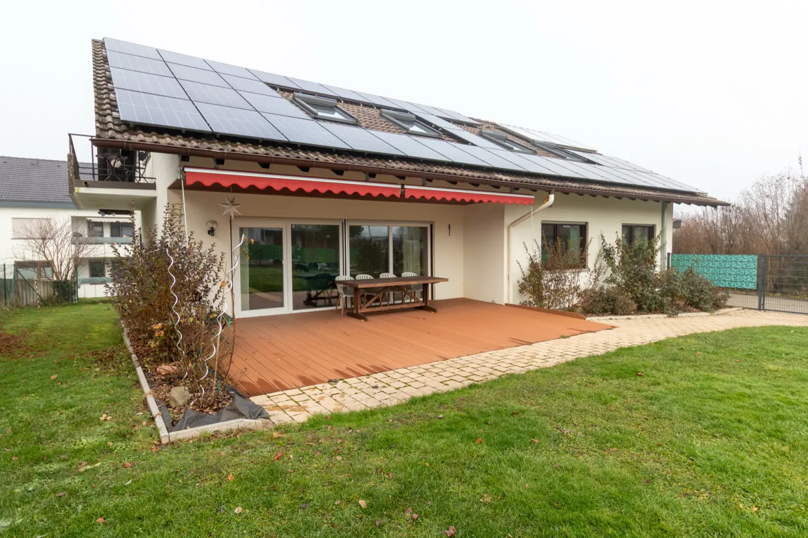 Gartenseite mit großer Holzterrasse und Photovoltaik auf dem Dach