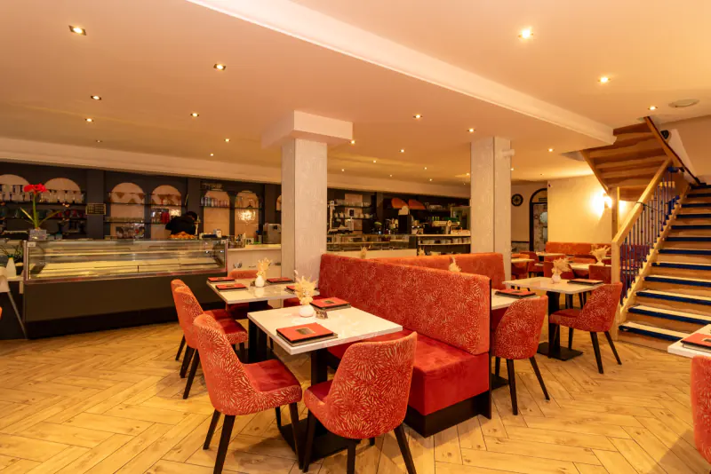 Gastraum des Cafés im Erdgeschoss mit Theke und Treppe
